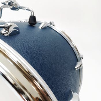 Detailed close-up of a blue drum with chrome details against a white background.