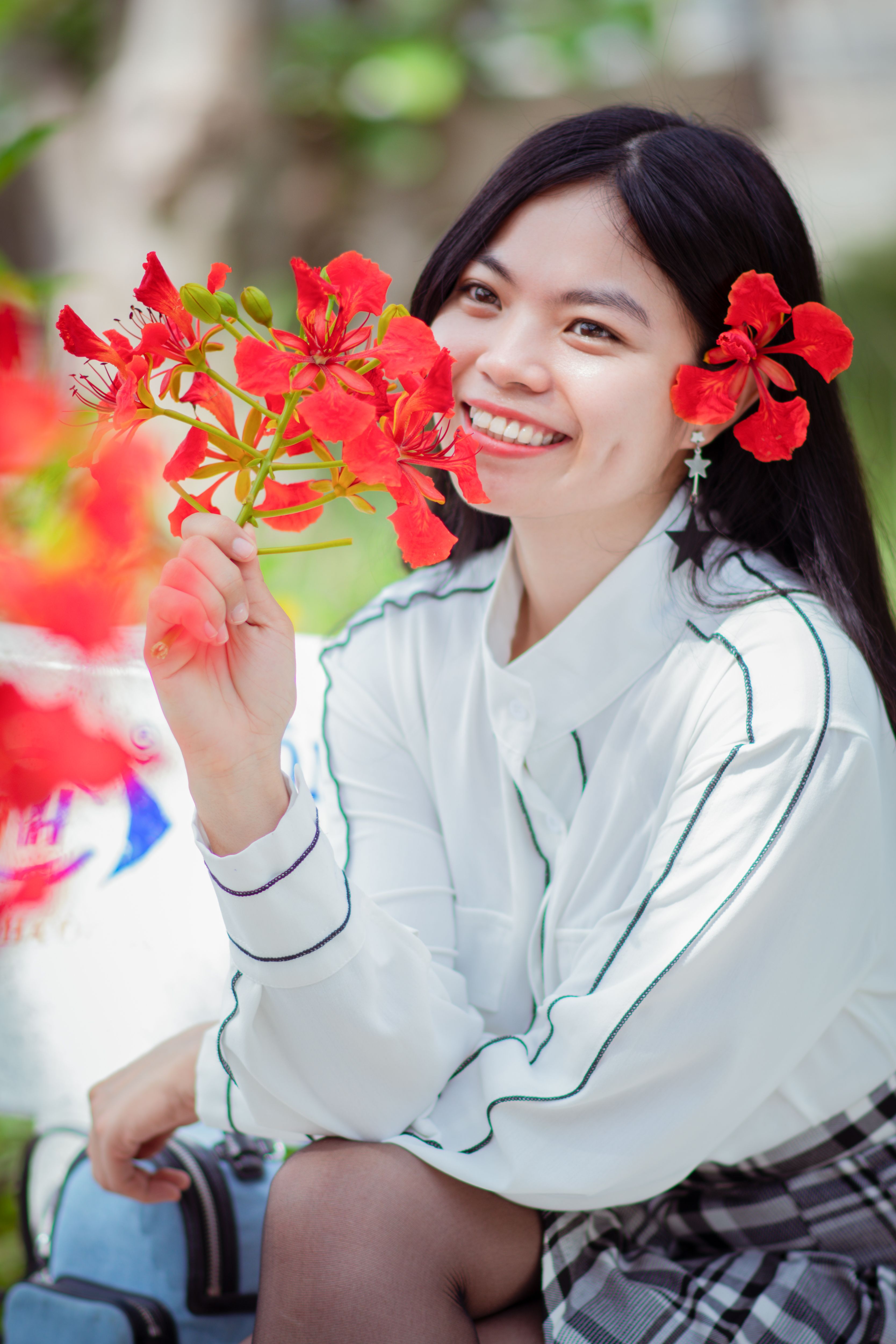 Happy teenager holding bright red flowers, enjoying spring outdoors.