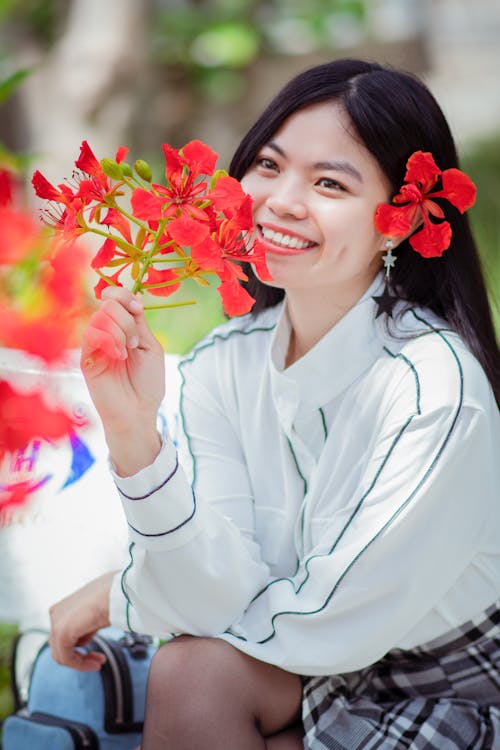 Teenage Girl Holding Red Flowers While Smiling
