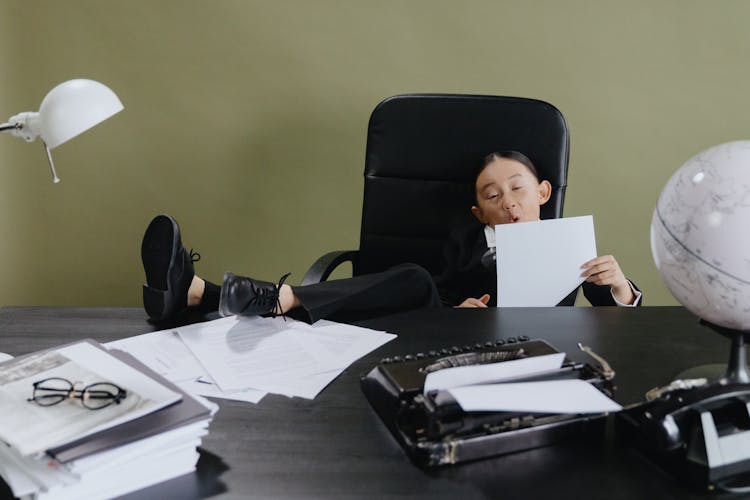 Girl Sitting On Office Chair Holding White Paper