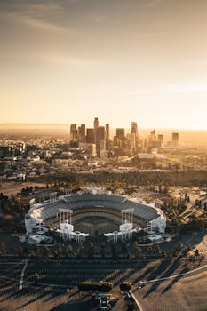 Stunning aerial shot of Dodger Stadium with Los Angeles skyline at sunset.
