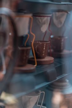 Close-up of artisanal ceramic coffee cups with decorative filters displayed on shelves.
