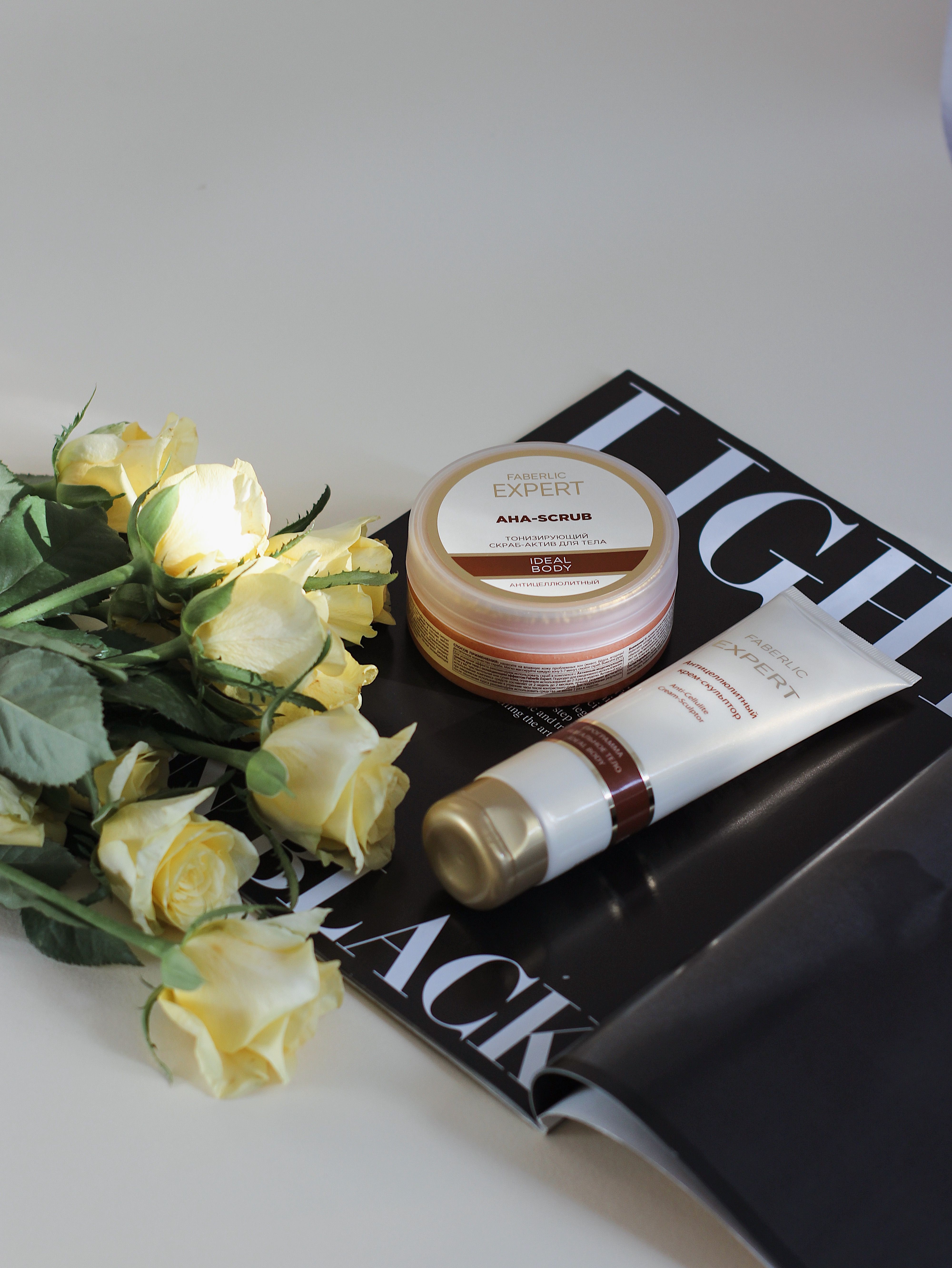 Aesthetic arrangement of skincare products with yellow roses on a magazine for beauty and lifestyle.