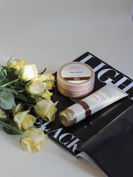 Aesthetic arrangement of skincare products with yellow roses on a magazine for beauty and lifestyle.
