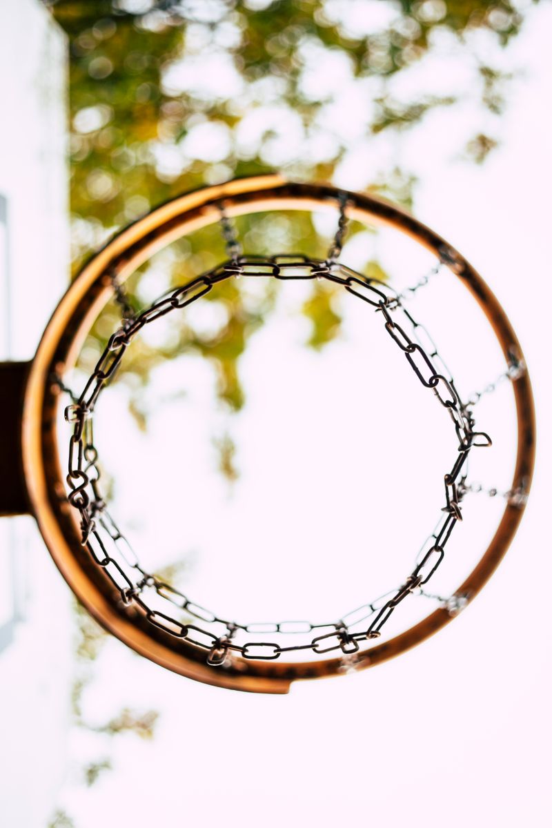 Basketball hoop with a chain net seen from below against bright sky — photo by Markus Spiske on Pexels