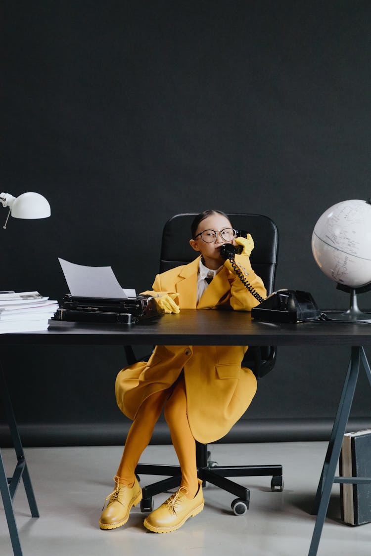 Asian Girl In Yellow Suit Sitting By Deck With Phone In Hand