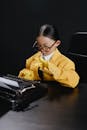 Asin girl in yelow suit typing on typewriter