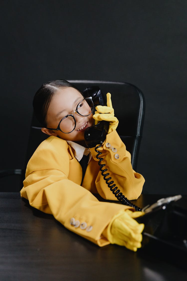 Asian Girl In Yellow Suit Sitting And Talking On Phone