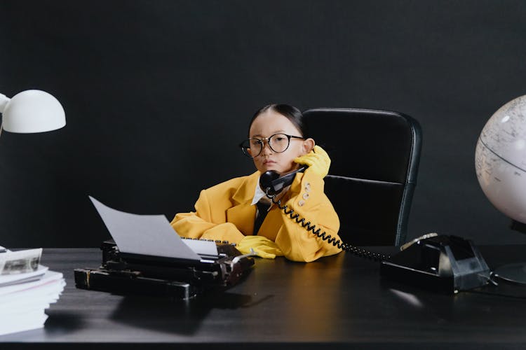 Asian Girl In Yellow Suit Sitting By Deck With Phone In Hand