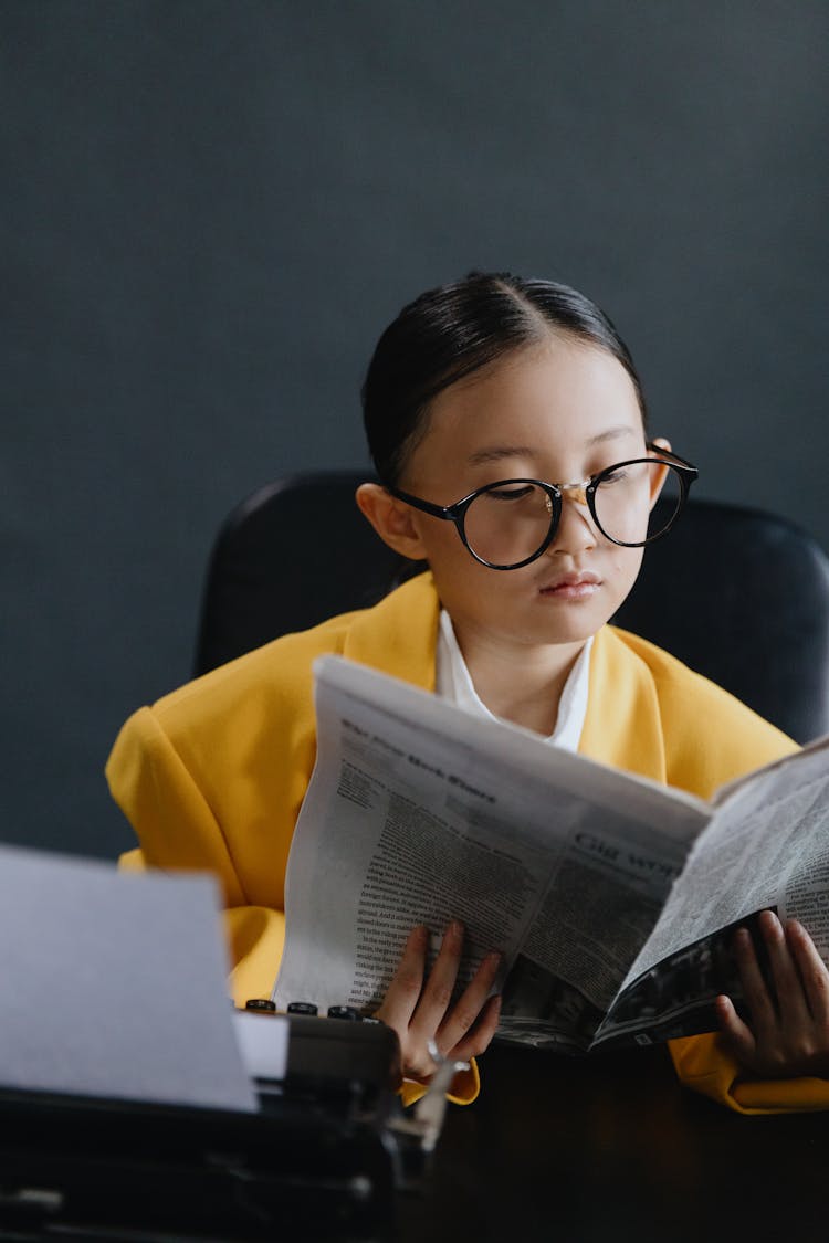 Asian Girl In Yellow Suit Reading Newspaper