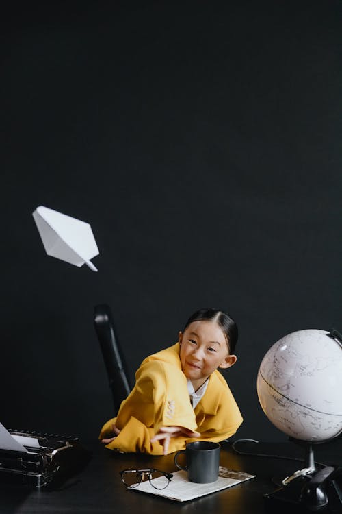 Asian girl looking at flying plane made from paper