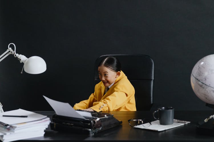 Asian Girl In Yellow Suit Sitting In Chair And Smiling