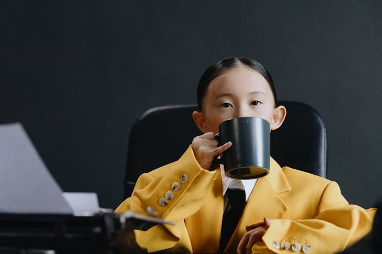 Asian Girl In Yellow Suit Drinking On Chair