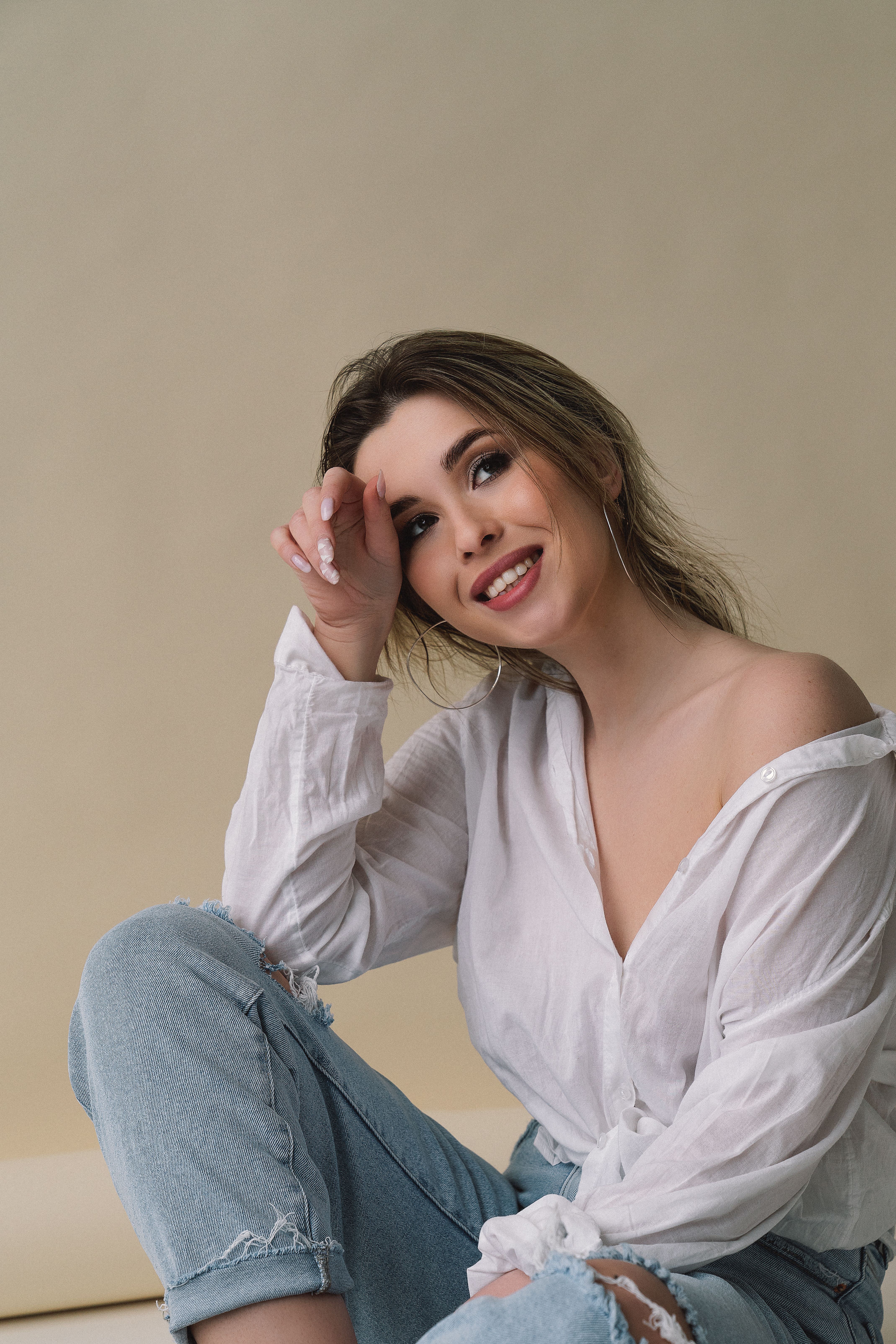 Portrait of a smiling woman in casual attire sitting indoors with a relaxed pose.