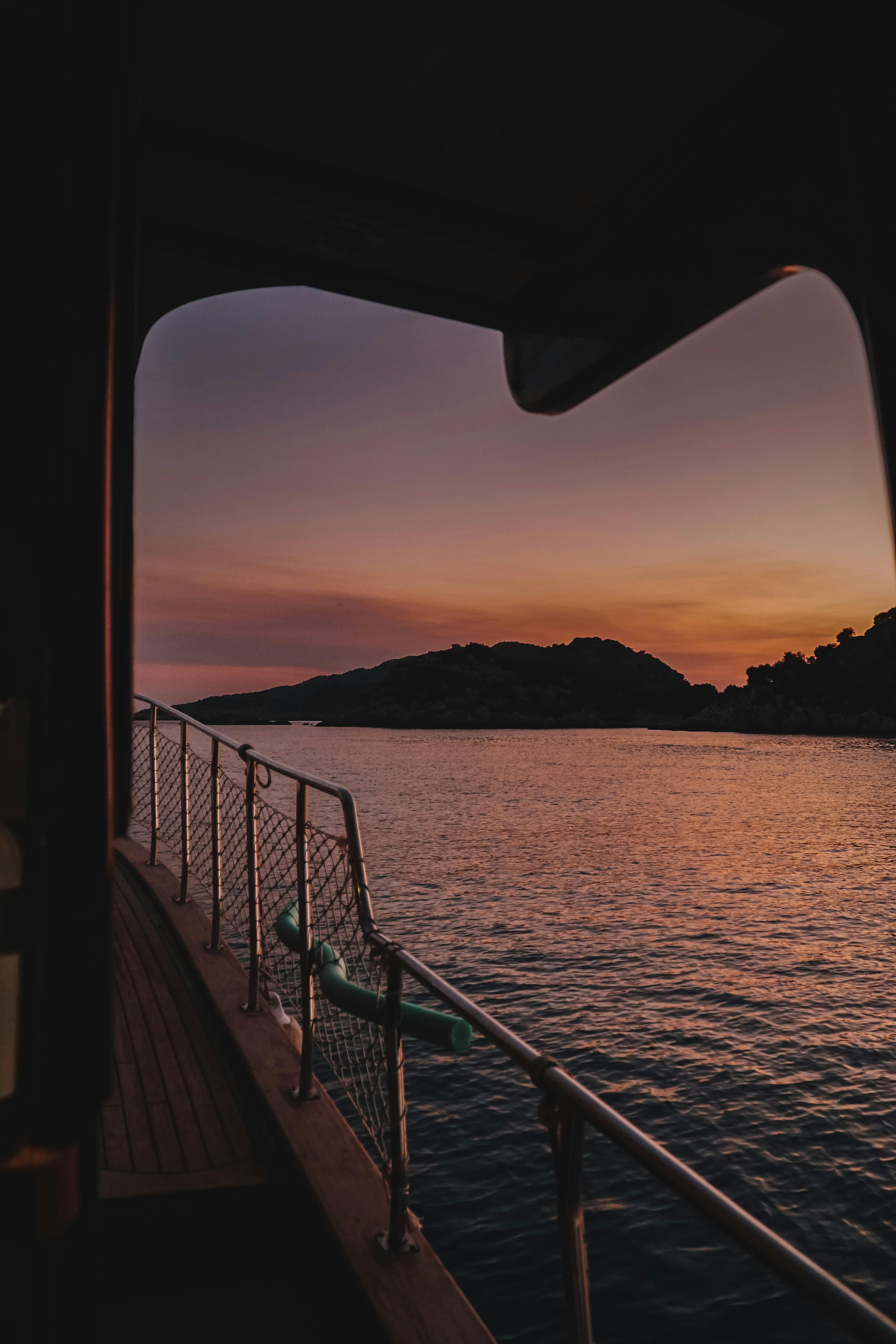 Serene boat deck view at sunset overlooking calm ocean waters and distant islands.