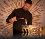 Man Wearing Black Dress Shirt Holding a Flute Glass and Black Wine Bottle