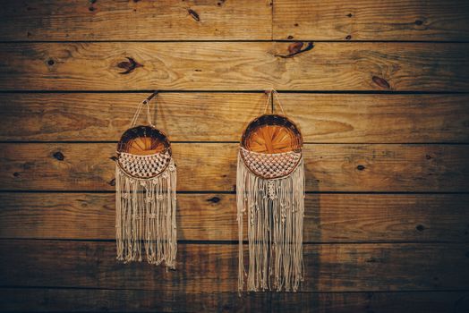 Handmade macrame and wicker baskets on warm wooden wall, perfect for rustic decor.
