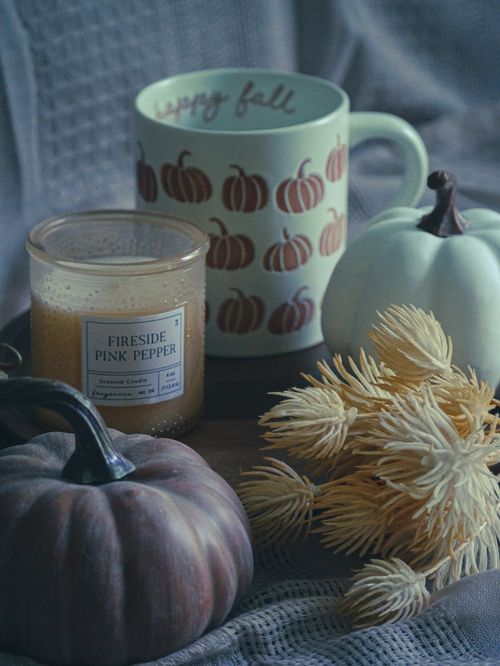 Free Cozy fall-themed setup with pumpkins, a mug, and a candle for seasonal warmth. Stock Photo
