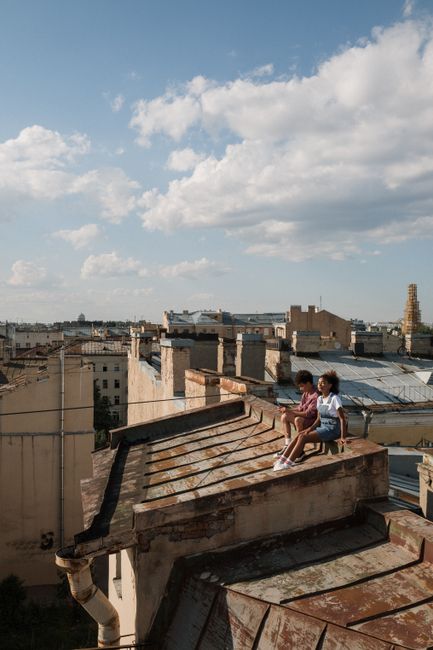 Teen couple sitting on a city rooftop enjoying the summer view in daylight.
