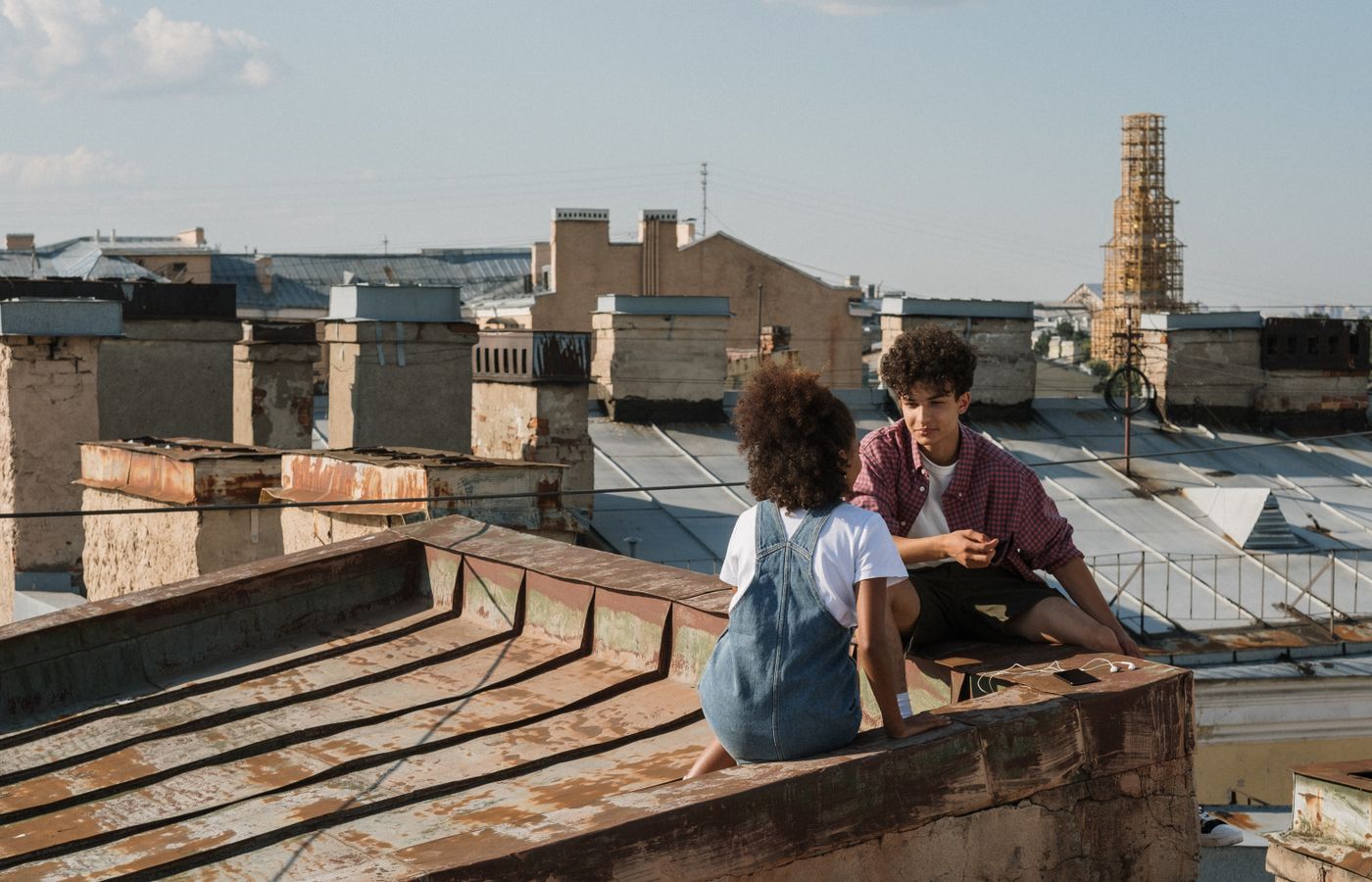 Teenagers enjoying a sunny day on a city rooftop, engaged in conversation and enjoying the view.