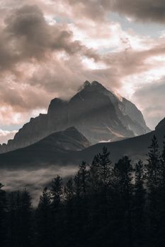 Majestic mountain peak shrouded in clouds and fog in the scenic Canadian Rockies.