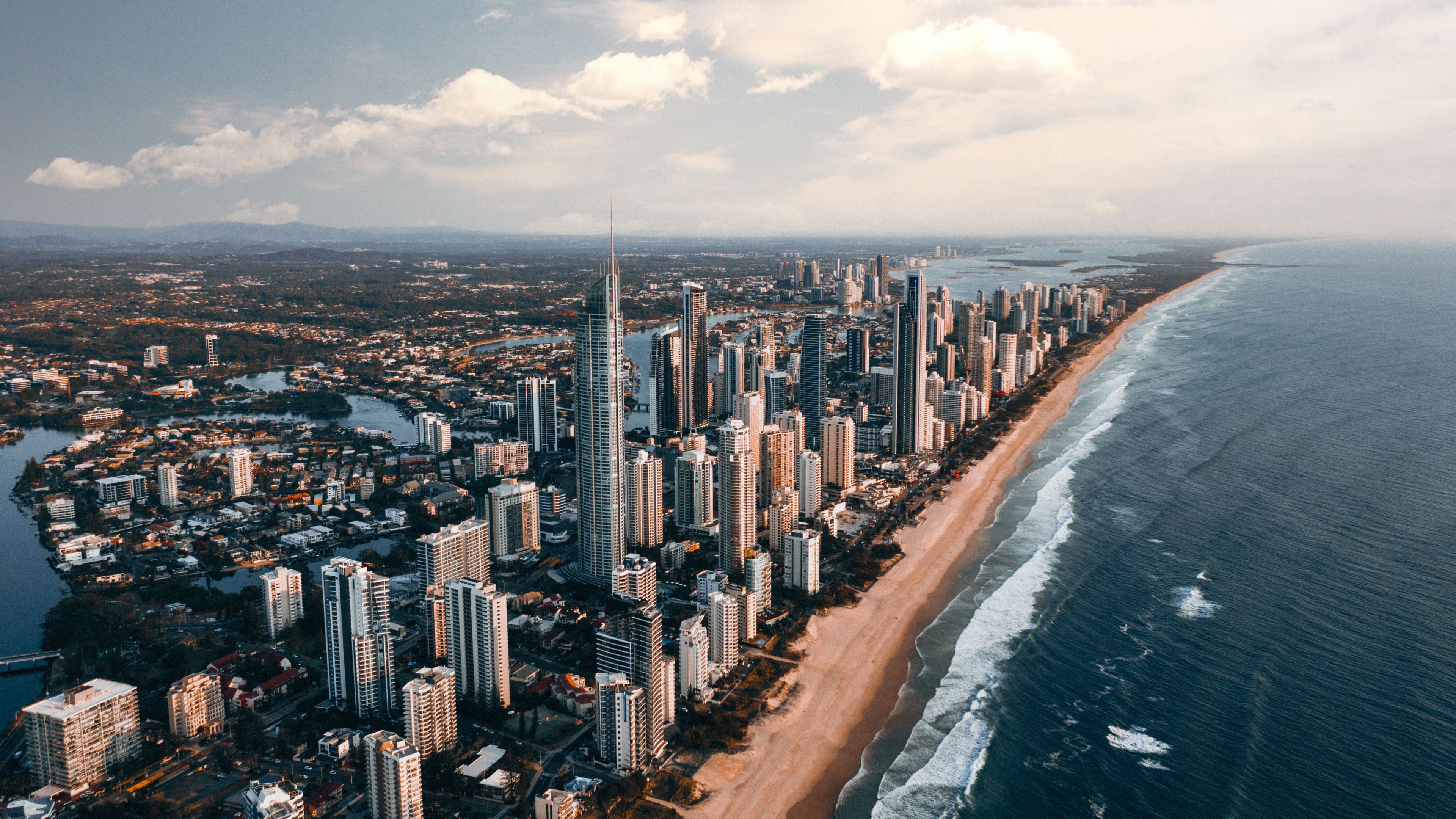 Breathtaking aerial view of Gold Coast skyline, beachfront, and ocean waves, capturing urban and natural beauty.