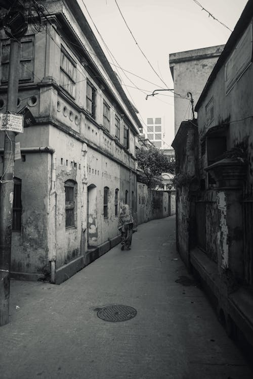 Woman Walking on a Narrow Alley Between Buildings