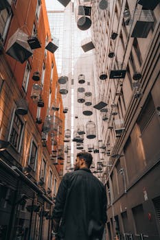 Caucasian man in city alleyway in Sydney with hanging birdcages above.