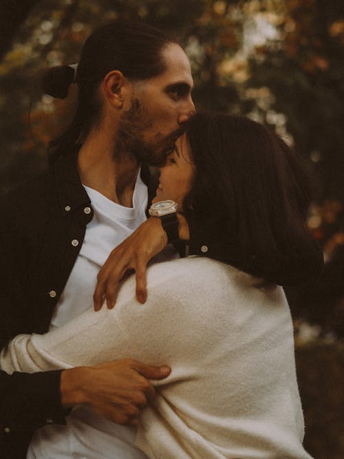 Photo of a Man Kissing a Woman on the Forehead