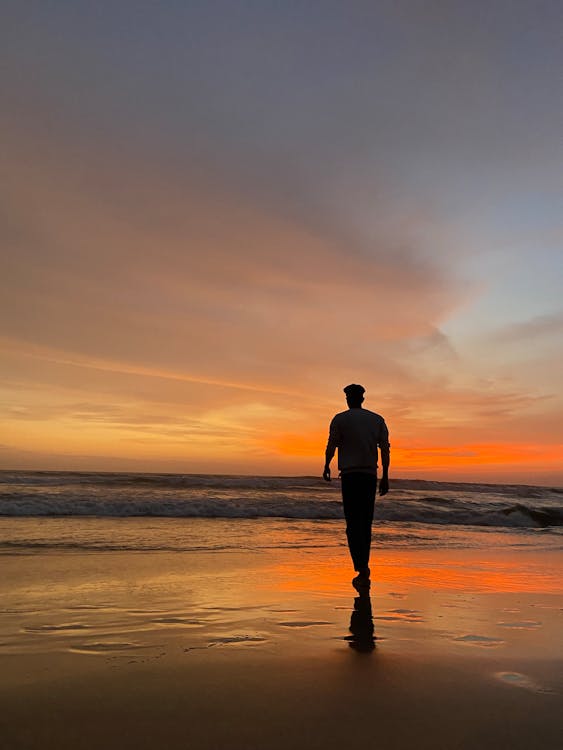 Silhouette of a Man on the Seashore During Sunset