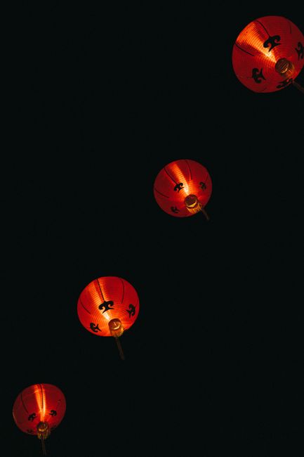 A night scene featuring illuminated red Chinese lanterns on a black background, symbolizing festive culture.