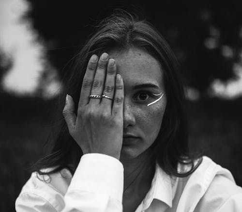 Grayscale Photo of a Woman Covering Her Eye with Her Hand