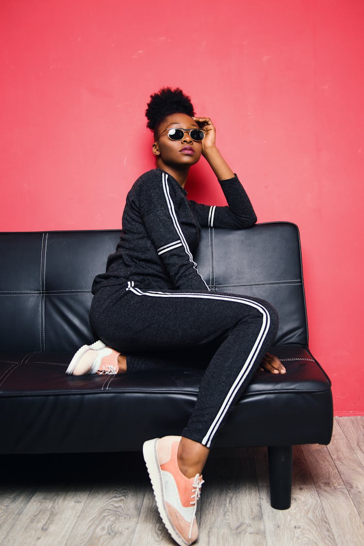 Woman Wearing Sunglasses Sits On Sofa Inside The Room