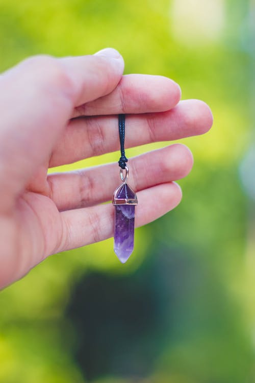 Free Person Holding Purple Gemstone Pendant Stock Photo