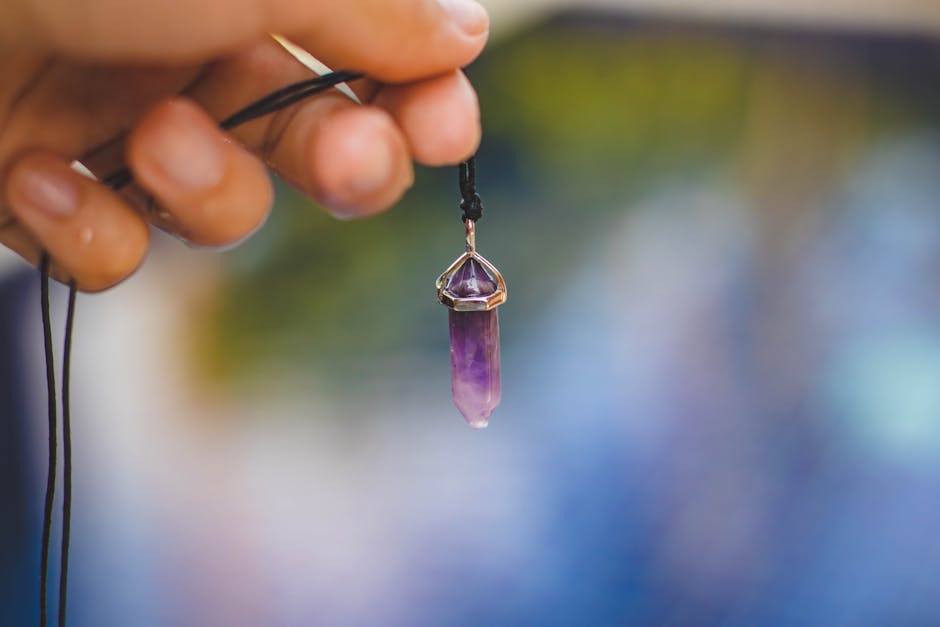 Hand holding an amethyst crystal pendant necklace with deep purple stone