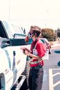 Man Wearing Red Polo Shirt Taking Order Beside a Car