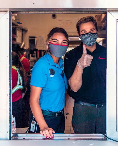 Free Drive-thru workers in masks showing thumbs up and smiling at the window. Stock Photo