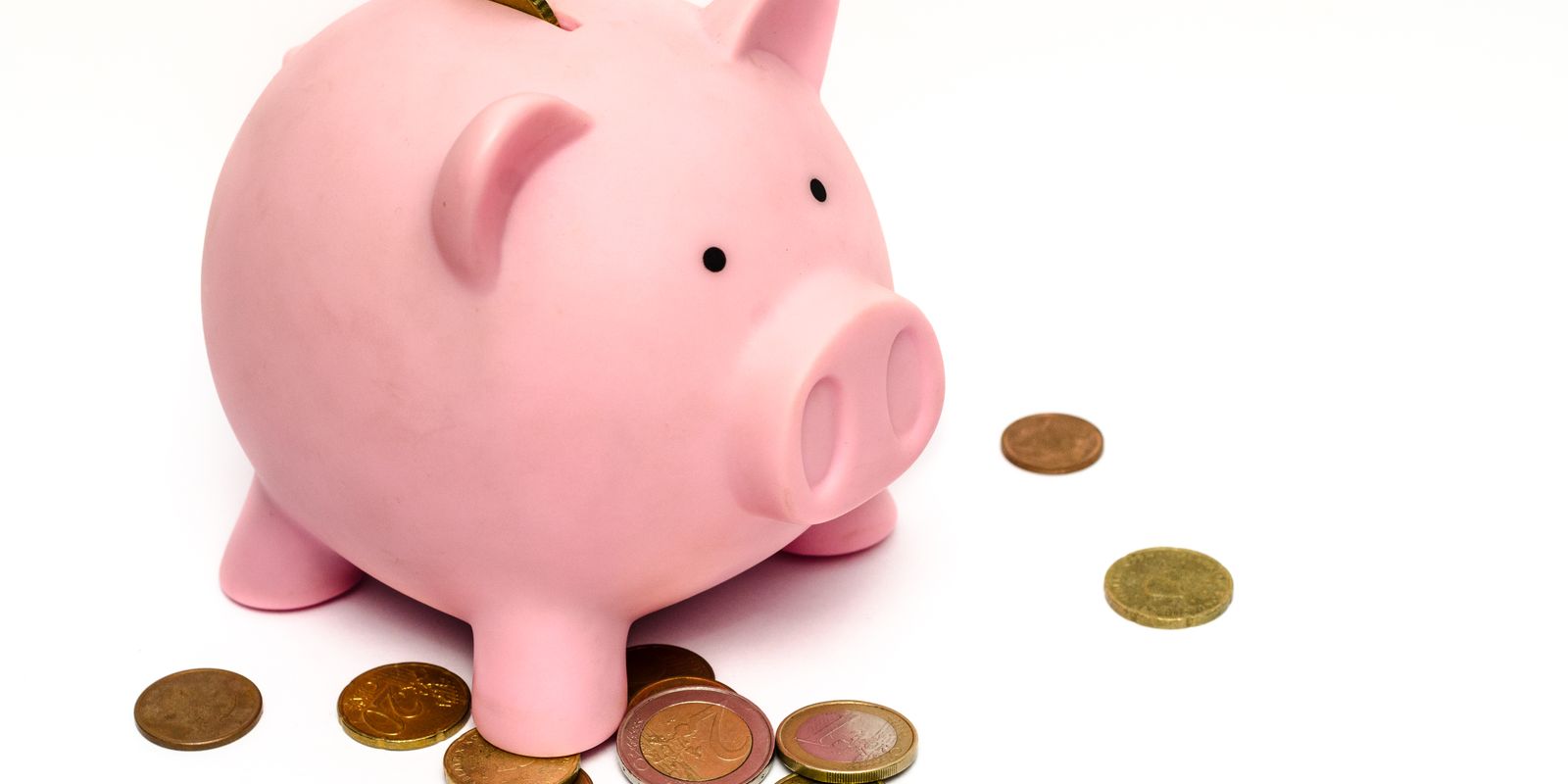 A pink piggy bank surrounded by scattered coins