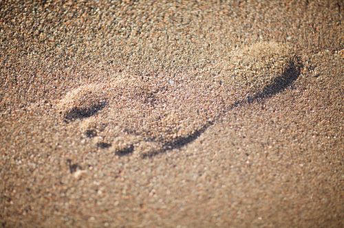 Free Close-up of a single footprint imprinted in the sand, showcasing natural texture and detail. Stock Photo