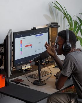 Man using headphones and microphone in home studio, engaging in podcast recording.