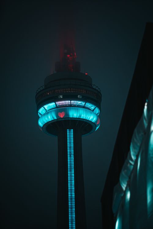 Free The iconic CN Tower glowing with blue and red lights against the night sky in Toronto, Canada. Stock Photo