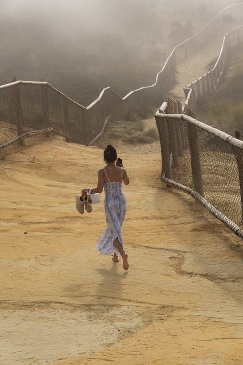 A Woman Walking on the Dirt Road