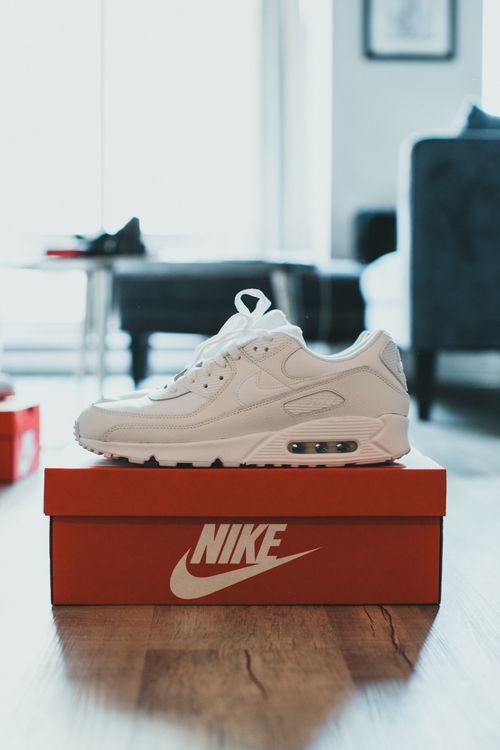 Free A sleek white sneaker placed on a Nike box in a modern home setting. Stock Photo