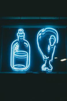 Bright neon signage depicting a bottle and chicken drumstick against a dark background, creating a vibrant ambiance.