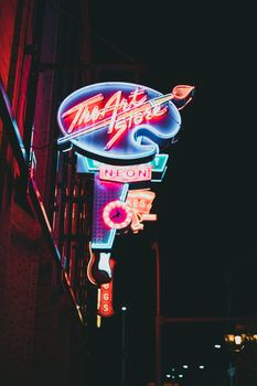 Illuminated neon art store sign glowing brightly at night in the city.
