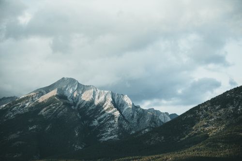 Free Snow-capped mountains under a moody sky, showcasing a serene and powerful landscape. Stock Photo