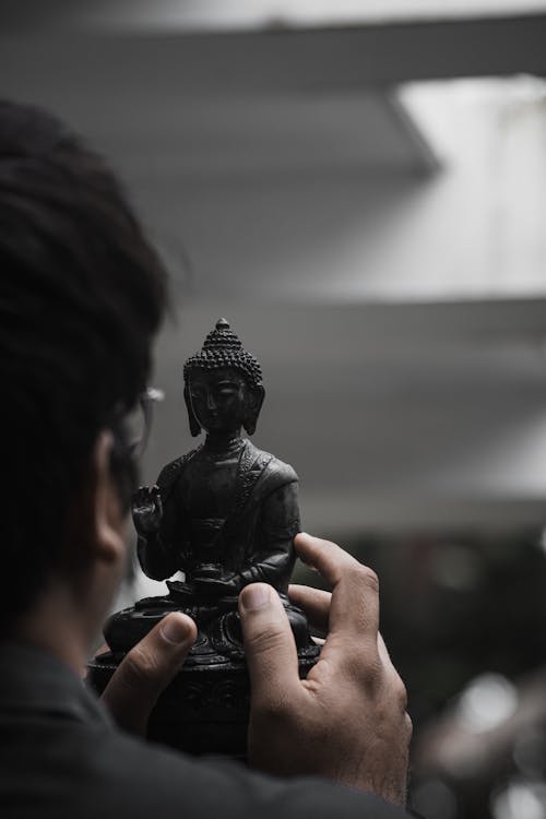 Person Holding Black Buddha Figurine