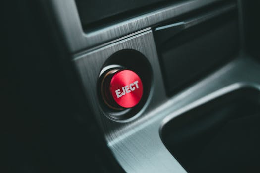 A detailed close-up of a red eject button in an electronic device, showcasing modern design.