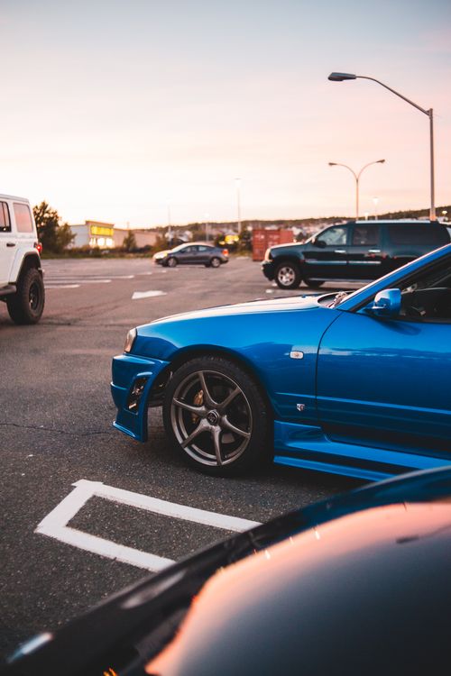 Free Vibrant blue sports car parked in a scenic urban parking lot during sunset. Stock Photo