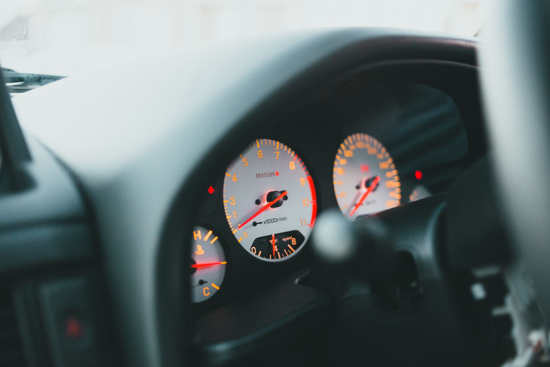 Close-up of car dashboard gauges with focus on illuminated speedometer and tachometer.